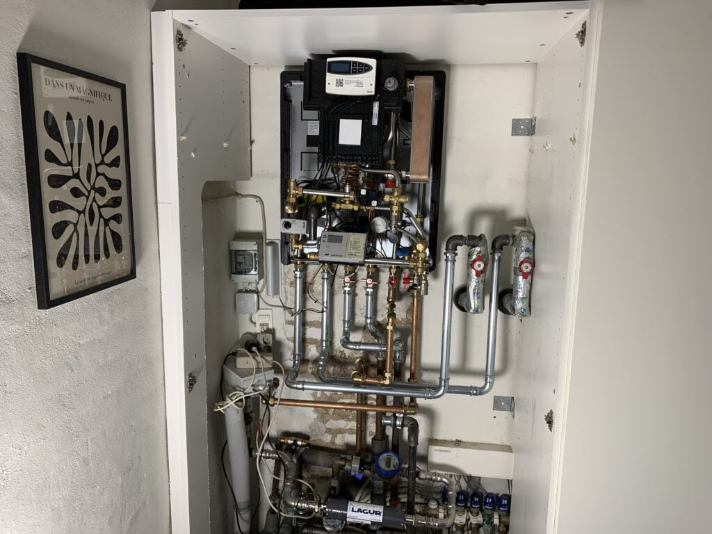 Varmeinstallation i skab med rør og målere.